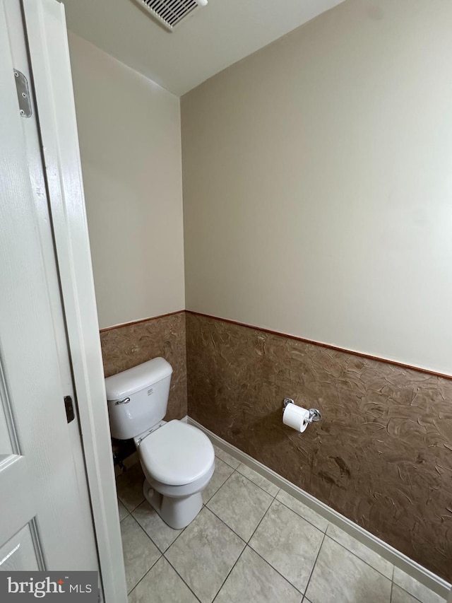 bathroom featuring tile patterned floors, toilet, and tile walls