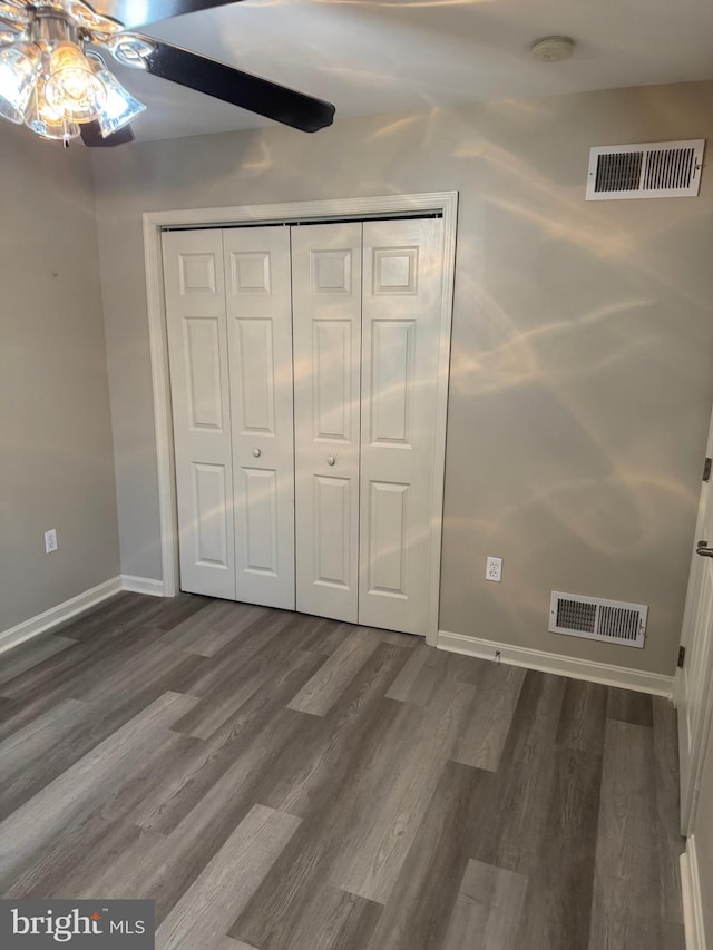 unfurnished bedroom featuring ceiling fan, dark hardwood / wood-style flooring, and a closet