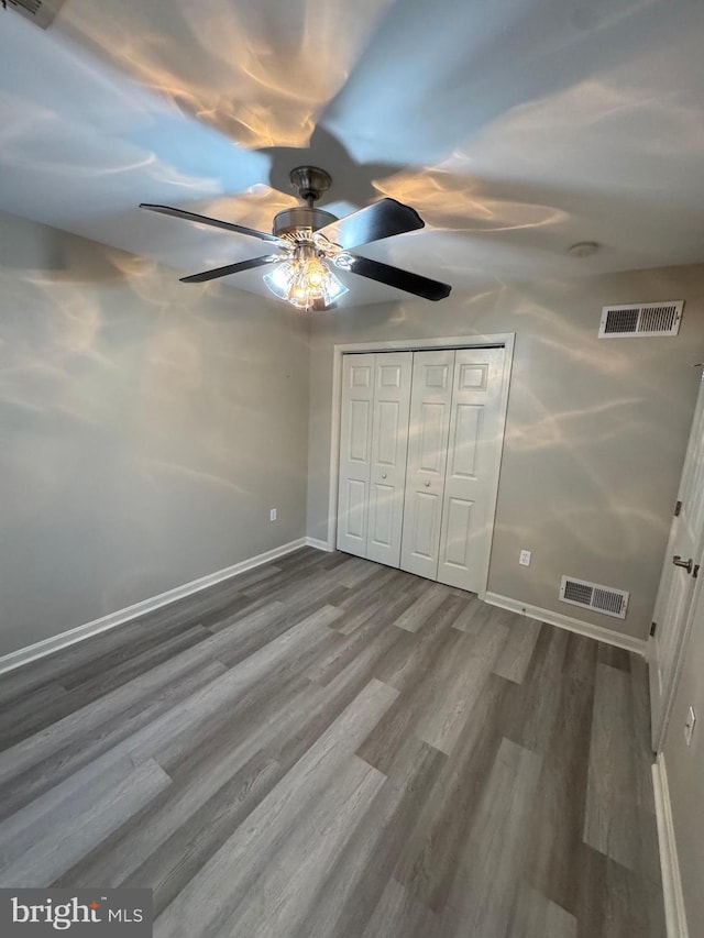 unfurnished bedroom with hardwood / wood-style flooring, ceiling fan, and a closet