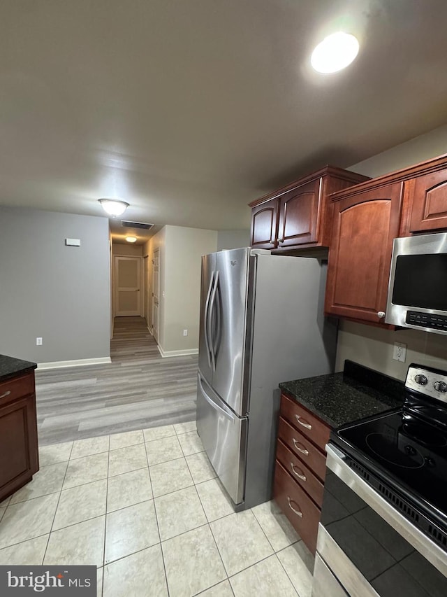 kitchen featuring dark stone counters, stainless steel appliances, and light wood-type flooring