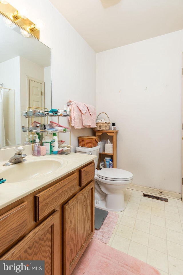 bathroom with toilet, vanity, and tile patterned floors