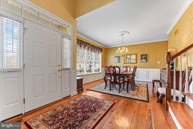 dining room with wood-type flooring, crown molding, and a notable chandelier