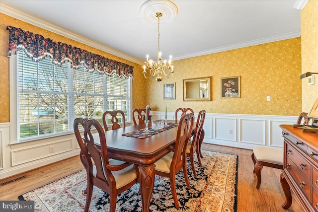 dining room featuring a chandelier, light hardwood / wood-style floors, and ornamental molding