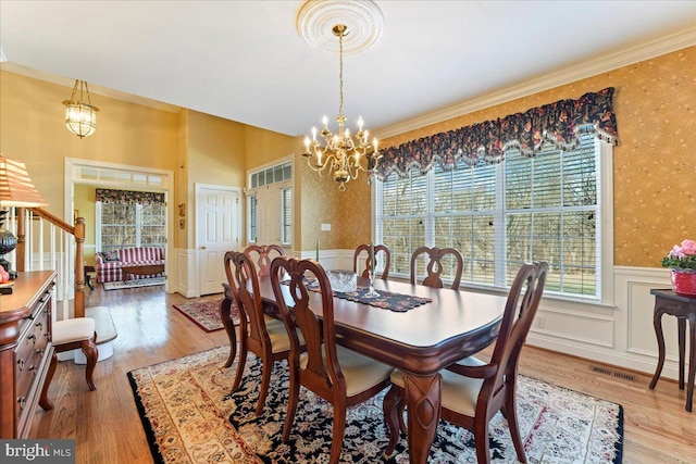 dining space featuring a chandelier, light hardwood / wood-style floors, and ornamental molding