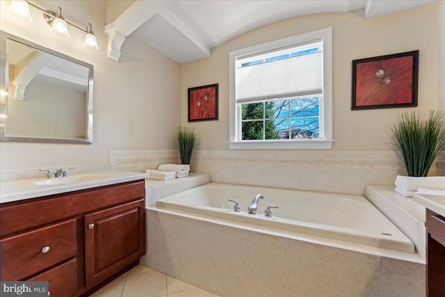 bathroom with tiled bath, vanity, and tile patterned flooring