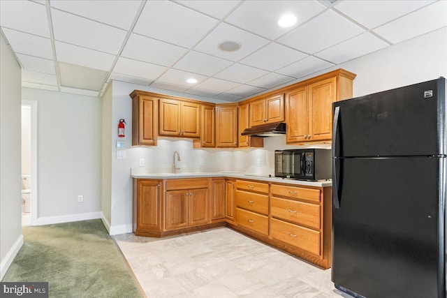 kitchen featuring black appliances, light colored carpet, a drop ceiling, and sink