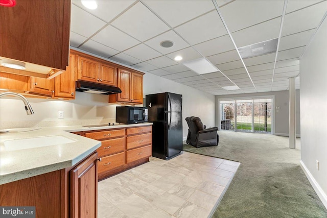 kitchen with black appliances, a paneled ceiling, light carpet, and sink