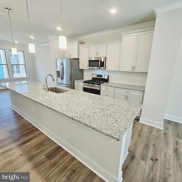 kitchen with sink, hanging light fixtures, stainless steel appliances, white cabinets, and light wood-type flooring