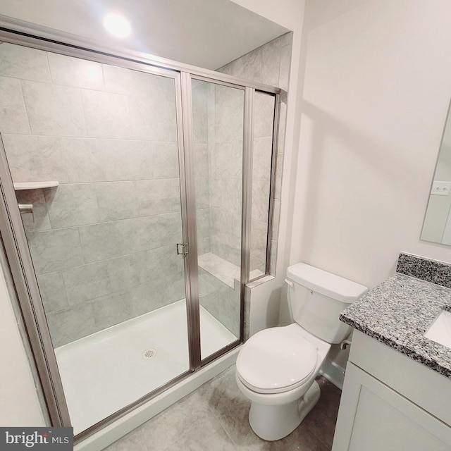 bathroom with tile patterned flooring, vanity, toilet, and a shower with shower door