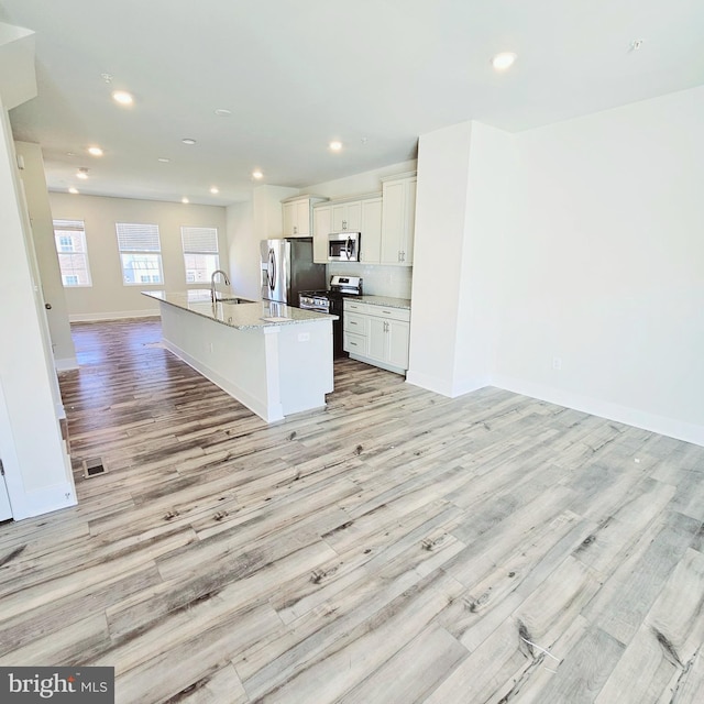 kitchen with sink, light wood-type flooring, an island with sink, and appliances with stainless steel finishes