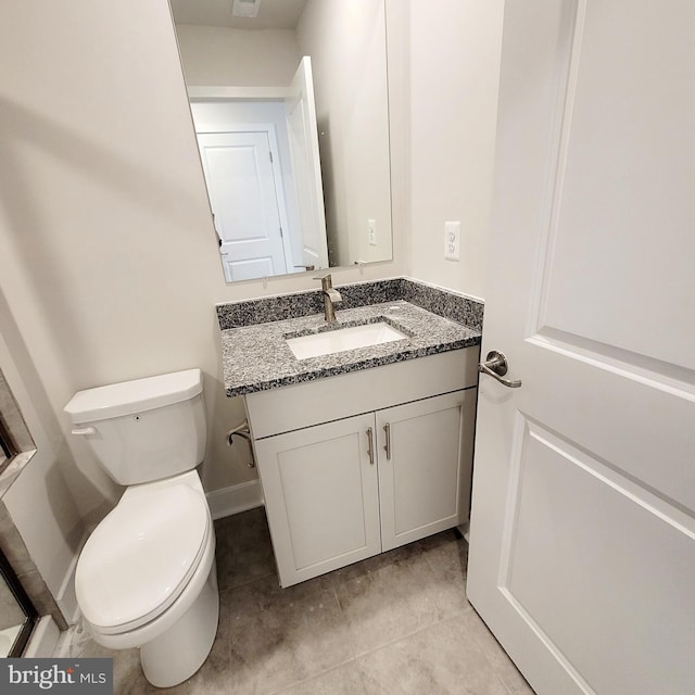 bathroom with toilet, vanity, and tile patterned floors