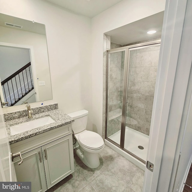 bathroom featuring tile patterned flooring, vanity, toilet, and a shower with door