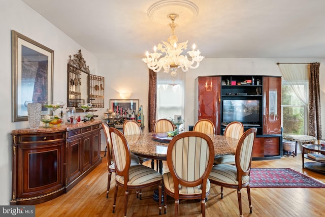 dining space with light wood-type flooring and an inviting chandelier