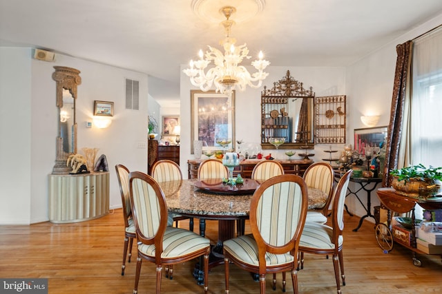 dining space with light hardwood / wood-style flooring and a notable chandelier