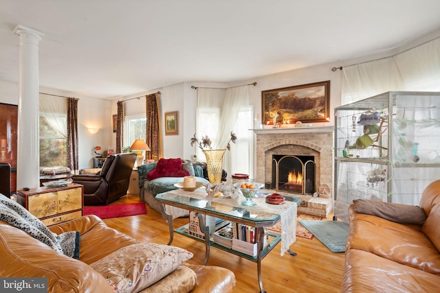 living room with hardwood / wood-style floors, decorative columns, and a brick fireplace