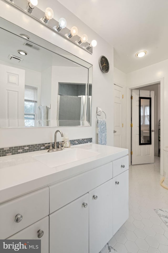 bathroom featuring tile patterned flooring, vanity, and decorative backsplash