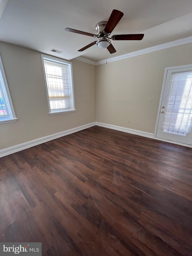 empty room featuring crown molding, ceiling fan, and dark wood-type flooring