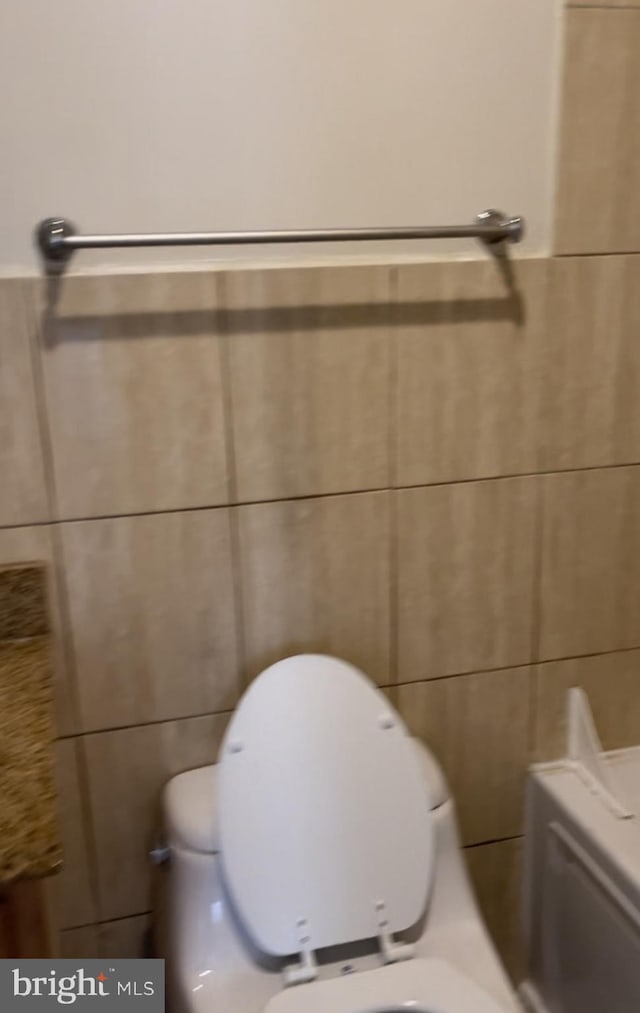 bathroom with toilet and tile walls