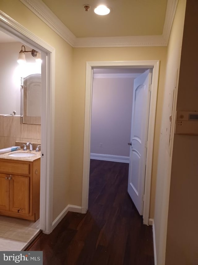 corridor featuring dark hardwood / wood-style flooring, ornamental molding, and sink