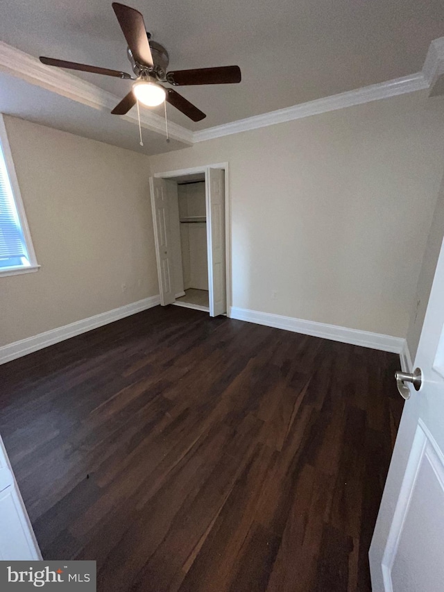 unfurnished bedroom with ceiling fan, dark hardwood / wood-style flooring, ornamental molding, and a closet