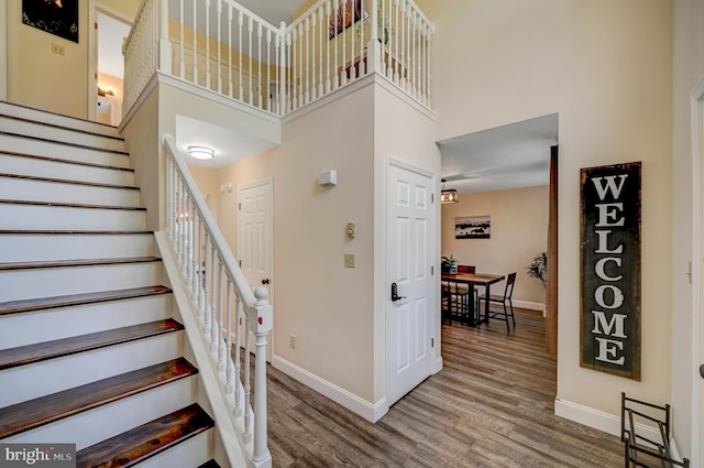 stairway featuring wood-type flooring and a high ceiling