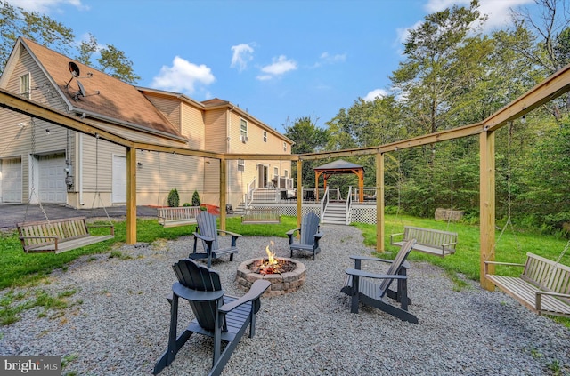 view of patio with a garage, a deck, and an outdoor fire pit