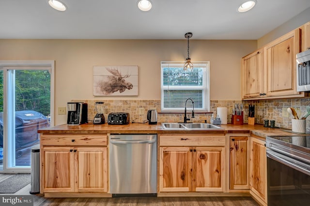 kitchen featuring sink, stainless steel appliances, decorative light fixtures, light brown cabinetry, and hardwood / wood-style flooring