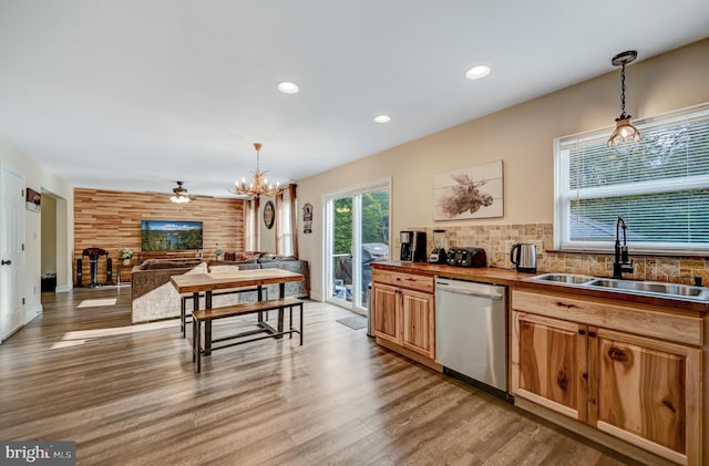 kitchen featuring stainless steel dishwasher, decorative light fixtures, light hardwood / wood-style floors, and sink