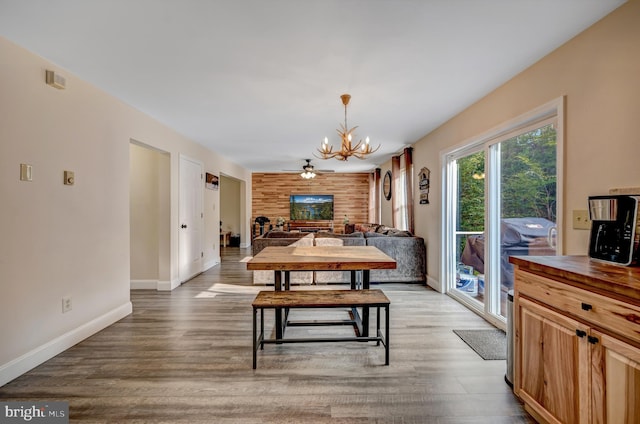 dining room with hardwood / wood-style flooring and ceiling fan with notable chandelier