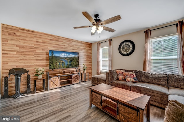 living room featuring wooden walls, ceiling fan, and light hardwood / wood-style floors