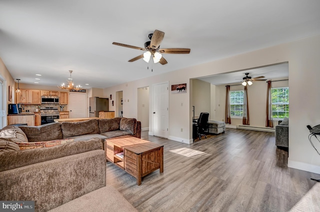 living room featuring ceiling fan with notable chandelier, light hardwood / wood-style floors, and a baseboard radiator