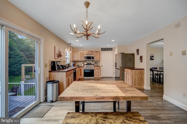 kitchen with sink, hanging light fixtures, light hardwood / wood-style floors, stainless steel appliances, and a chandelier