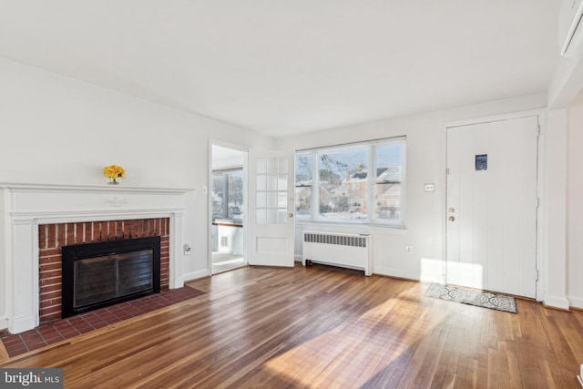 unfurnished living room featuring a fireplace, radiator heating unit, and dark hardwood / wood-style floors