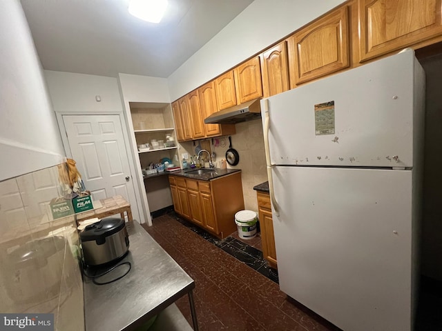 kitchen featuring backsplash, white fridge, and sink