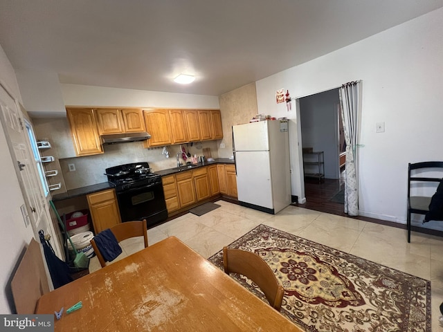 kitchen featuring black gas range, white refrigerator, and sink