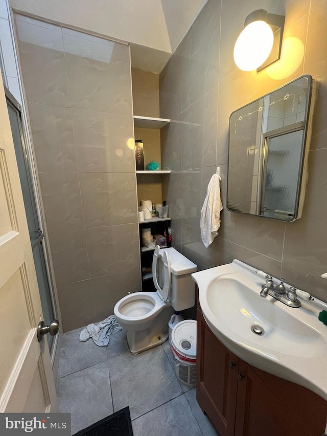 bathroom with an enclosed shower, vanity, tile patterned floors, and tile walls