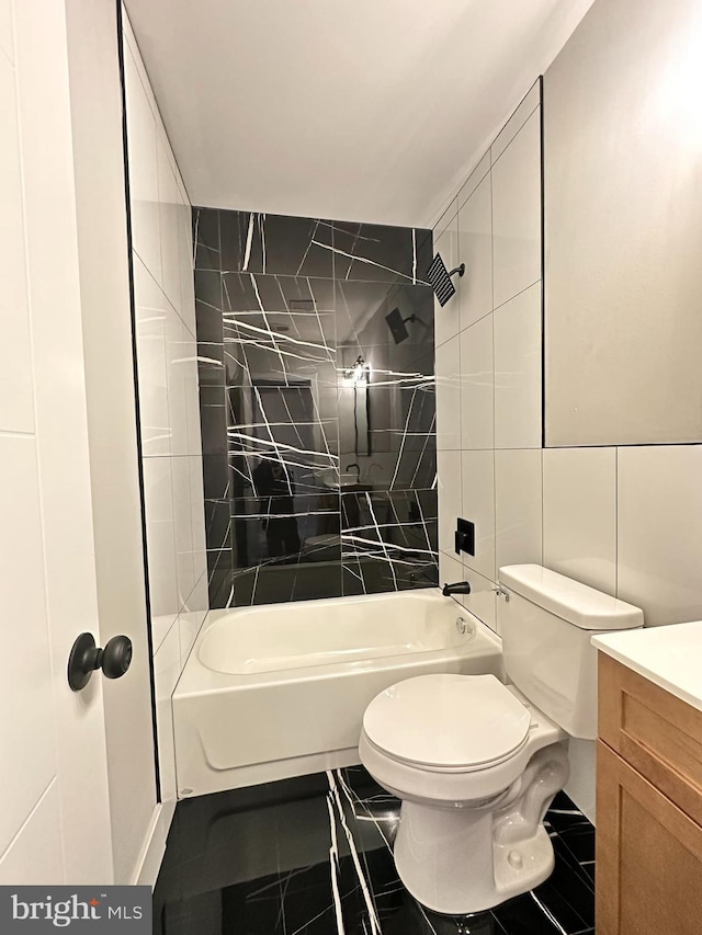 full bathroom featuring tile patterned floors, vanity, tile walls, toilet, and tiled shower / bath