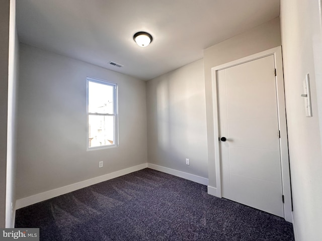 empty room featuring dark carpet