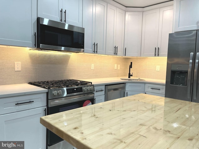 kitchen with butcher block counters, white cabinetry, sink, decorative backsplash, and appliances with stainless steel finishes