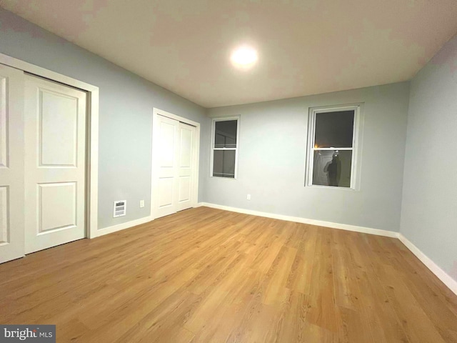 unfurnished bedroom featuring light hardwood / wood-style floors and multiple closets