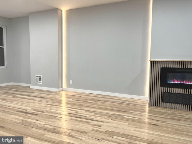 unfurnished living room featuring a fireplace and light hardwood / wood-style flooring