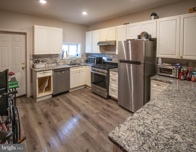 kitchen featuring light stone countertops, stainless steel appliances, sink, white cabinets, and dark hardwood / wood-style floors