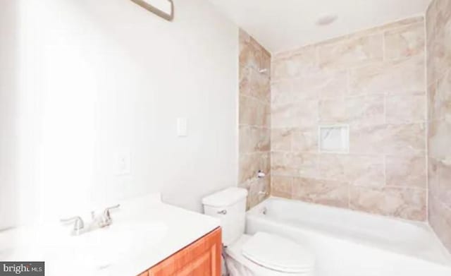 full bathroom featuring vanity, tiled shower / bath combo, and toilet