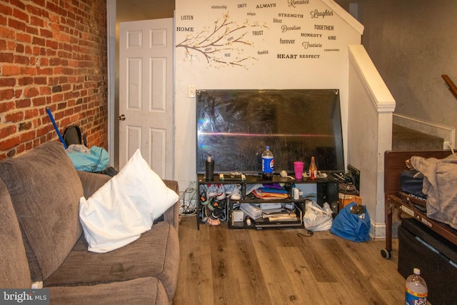 living room featuring hardwood / wood-style flooring and brick wall