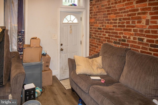 living room with hardwood / wood-style floors and brick wall