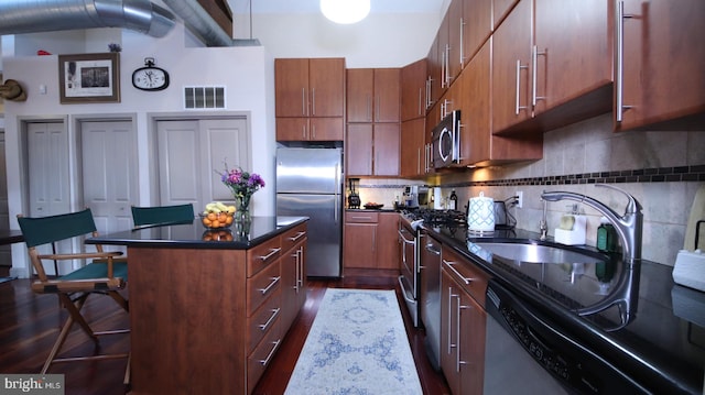 kitchen featuring a center island, sink, stainless steel appliances, dark hardwood / wood-style floors, and a breakfast bar