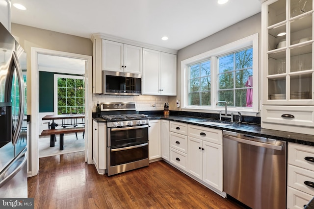 kitchen featuring white cabinetry, sink, dark wood-type flooring, stainless steel appliances, and dark stone counters