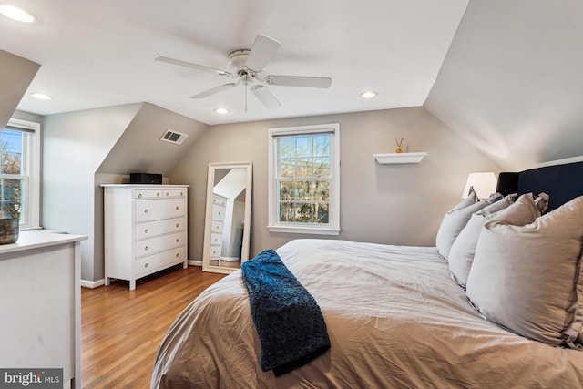 bedroom featuring ceiling fan, light hardwood / wood-style flooring, multiple windows, and vaulted ceiling