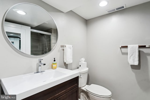 bathroom with an enclosed shower, vanity, and toilet