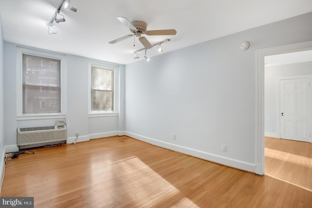 unfurnished room with a wall mounted air conditioner, ceiling fan, and wood-type flooring